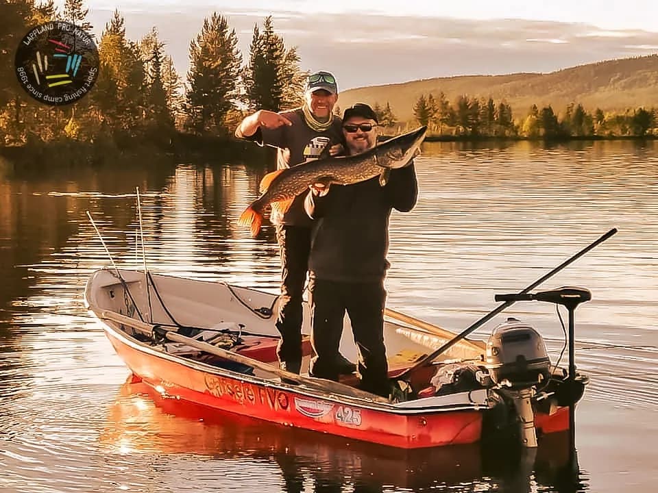 Deux pêcheurs et un brochet dans un bateau, lumière du soir